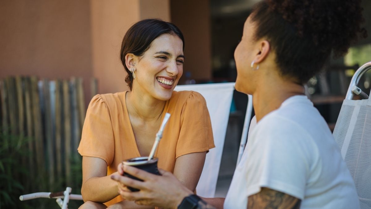Foto de dos mujeres tomando mate y riendo.